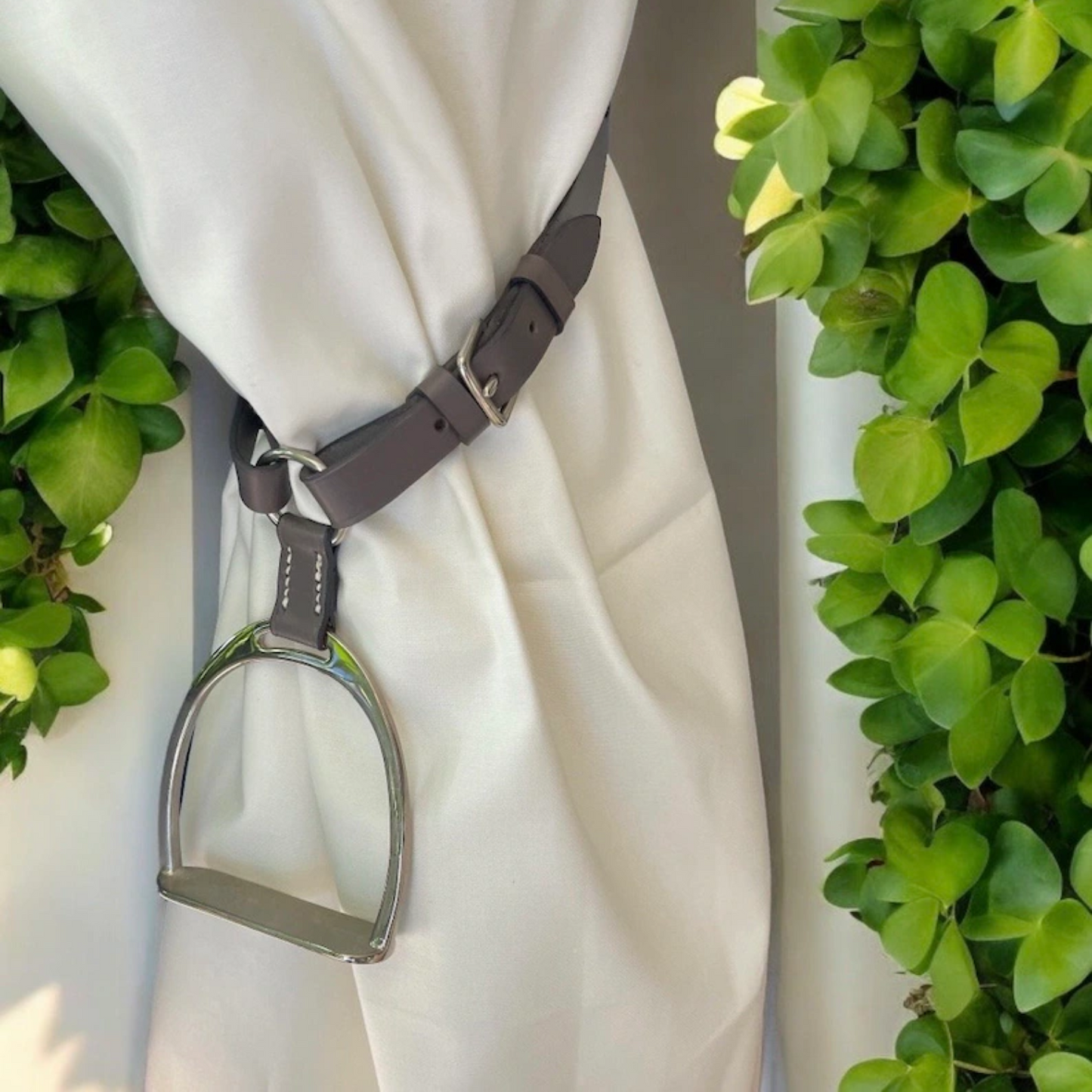 Miniature stirrup iron leather curtain tie backs.